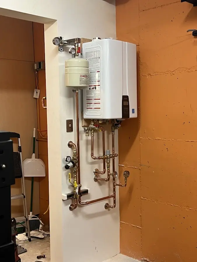 Plumbing technician inspecting water heater connections in West Lafayette
